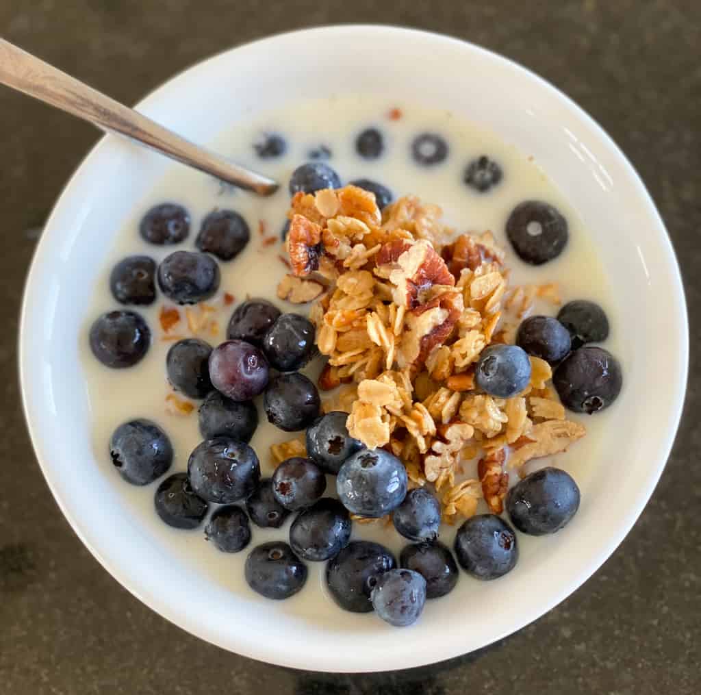 a bowl of simple homemade granola  blueberries milk