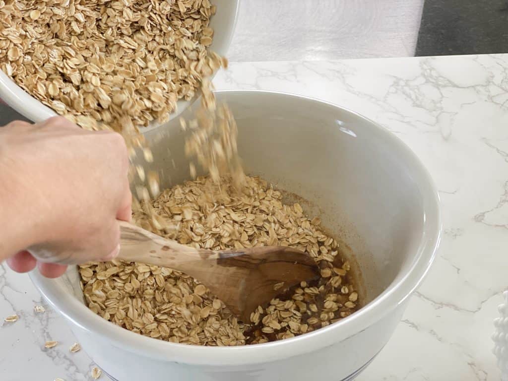 pouring oats into bowl for granola