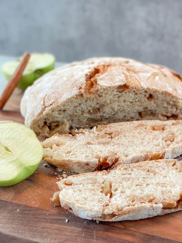 sliced loaf of sourdough apple bread on wood cutting board