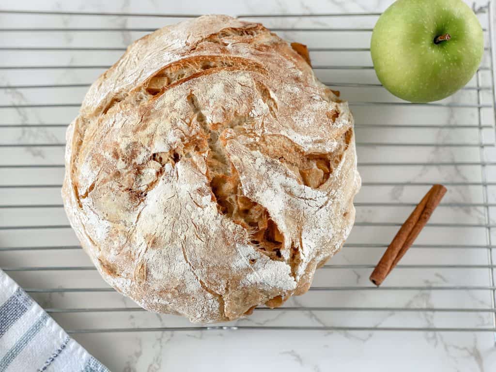 sourdough apple bread round cooling on bakers rack