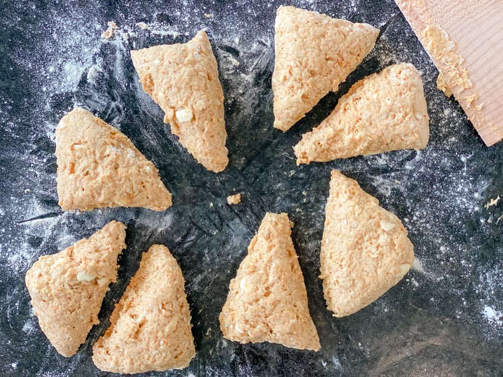 pumpkin scone dough cut into triangles on a countertop